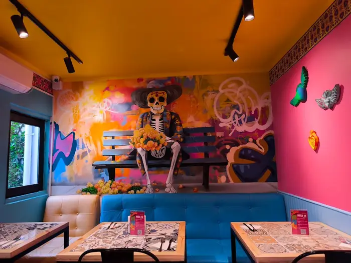 Salón con mural de catrina y bancas
